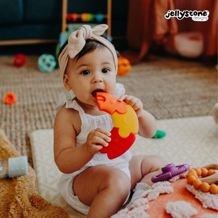 Dziewczynka gryzie silikonowy segment puzzli Jellystone – bezpieczna zabawka do ząbkowania